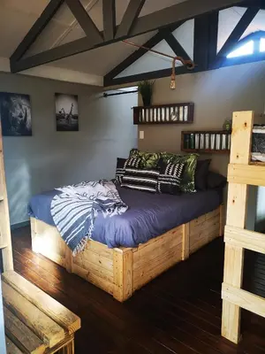 a bedroom with a wooden bed with pillows on it at Treur River Lodge in Moremela