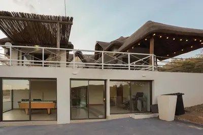 a house with a thatched roof with a table at Hinda Mountain Lodge Mabalingwe in Mabula