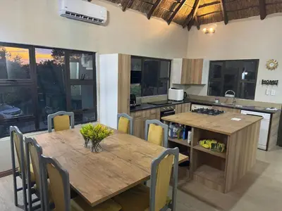 a kitchen with a wooden table and chairs in a kitchen at Hinda Mountain Lodge Mabalingwe in Mabula