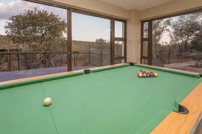a snooker room with a pool table andwindows at Hinda Mountain Lodge Mabalingwe in Mabula