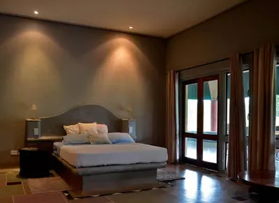a bedroom with a bed and a large window at Tingala Lodge - Bed in the Bush in Phalaborwa