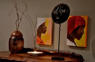 a table with a vase and two paintings on the wall at Tingala Lodge - Bed in the Bush in Phalaborwa