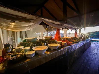 a buffet line with bowls and plates of food at Nkambeni Safari Camp in Hazyview