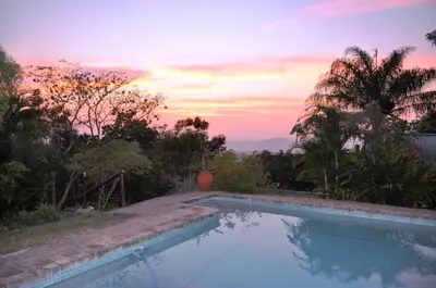 a swimming pool with a sunset in the background at Impala Niezel Lodge & Guest House in Hazyview