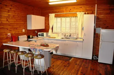 a kitchen with a white refrigerator and a counter with stools at Impala Niezel Lodge & Guest House in Hazyview