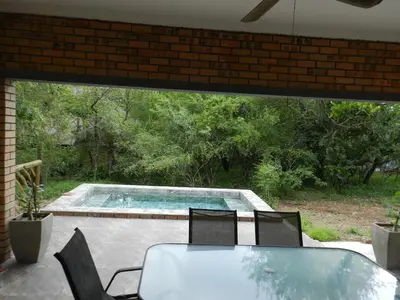 a patio with a table and chairs and a swimming pool at BUFFALO in Marloth Park