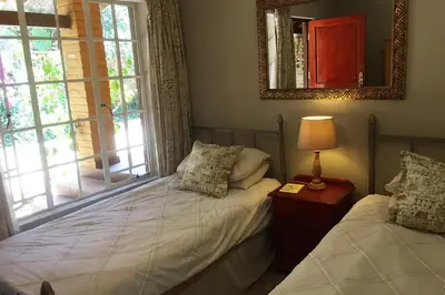 a bedroom with two twin beds and a mirror at Roosters Nest BnB in Midrand