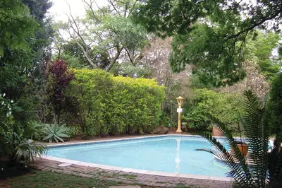 a swimming pool in a yard with trees and bushes at Roosters Nest BnB in Midrand