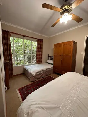 a bedroom with two beds and a ceiling fan at Roosters Nest BnB in Midrand
