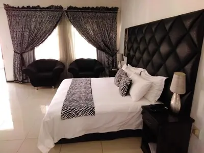 a bedroom with a bed with a black and white comforter at Big Ben Lodge in Polokwane