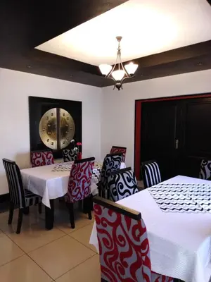 a dining room with tables and chairs and a chandelier at Big Ben Lodge in Polokwane