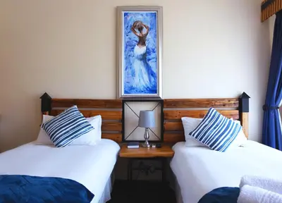 two beds in a room with a picture on the wall at Gorgeous Gecko Guesthouse in Modimolle