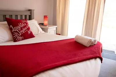 a red and white bed with a red blanket on it at Gorgeous Gecko Guesthouse in Modimolle