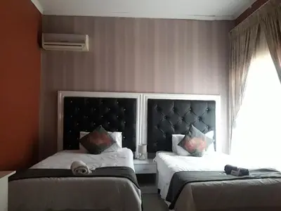 a bedroom with two beds and a window at Vakhusi Guesthouse in Malamulele