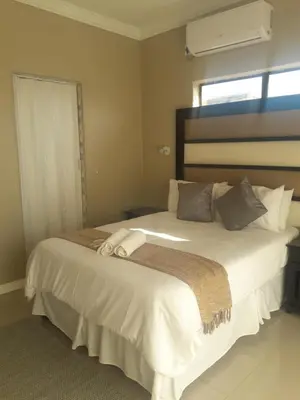 a bedroom with a large white bed with a window at Vakhusi Guesthouse in Malamulele
