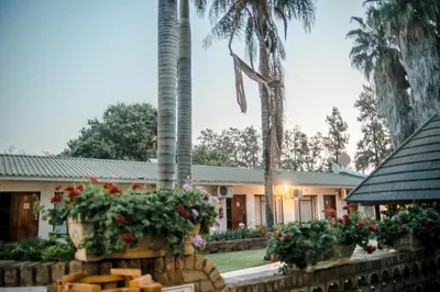 a house with palm trees and flowers in front of it at Loskop Valley Lodge in Groblersdal