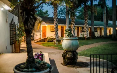 a house with palm trees in front of it at Loskop Valley Lodge in Groblersdal