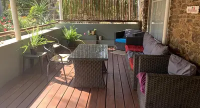 a porch with a table and chairs and a couch at Shala Mushe Tented Camp & Camp in Bela-Bela