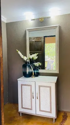 a mirror on top of a cabinet with flowers on it at Riverside's Kaia in Dudu