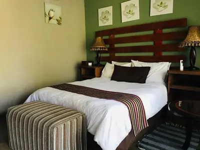 a bedroom with a large white bed with a wooden headboard at Riverside's Kaia in Dudu