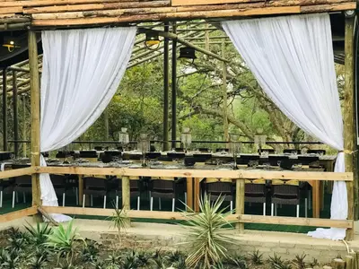 a set up for a wedding in a pavilion with white curtains at Riverside's Kaia in Dudu