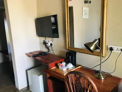 a wooden desk with a mirror and a lamp on it at Riverside's Kaia in Dudu