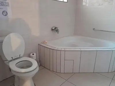 a white bathroom with a tub and a toilet at RS GARDEN GUESTHOUSE in Thohoyandou