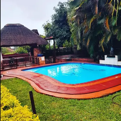 a swimming pool in a yard with a table and a bench at RS GARDEN GUESTHOUSE in Thohoyandou