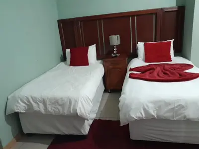 a bedroom with two beds with red pillows at RS GARDEN GUESTHOUSE in Thohoyandou