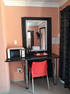 a room with a desk with a microwave and a red chair at RS GARDEN GUESTHOUSE in Thohoyandou