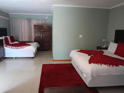 a bedroom with two beds and a red rug at RS GARDEN GUESTHOUSE in Thohoyandou