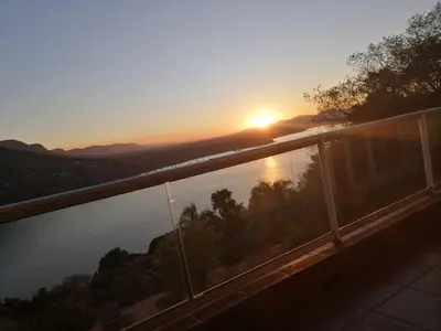a sunset from a balcony with a view of the water at Letamong in Hartbeespoort