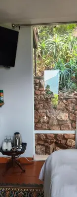 a bedroom with a window with a stone wall at Letamong in Hartbeespoort