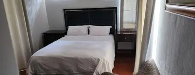 a bedroom with a large bed with white sheets and pillows at Letamong in Hartbeespoort