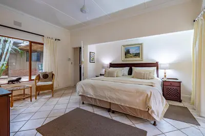 a bedroom with a bed and a table and a chair at Mhlati Guest Cottages in Malelane