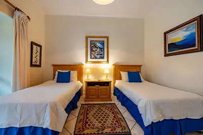 a room with two beds and a table at Mhlati Guest Cottages in Malelane