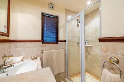 a bathroom with a shower and a sink at Mhlati Guest Cottages in Malelane