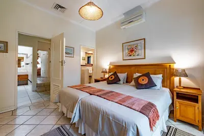 a bedroom with a large bed and a bathroom at Mhlati Guest Cottages in Malelane