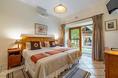 a bedroom with a large bed and a window at Mhlati Guest Cottages in Malelane