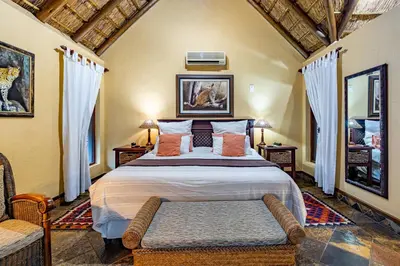 a bedroom with a large bed in a room at Mhlati Guest Cottages in Malelane