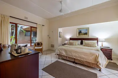 a bedroom with a bed and a desk in a room at Mhlati Guest Cottages in Malelane