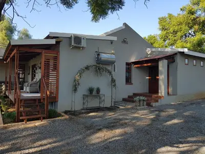 a white house with a porch and a driveway at El-Ruze in Baviaanspoort