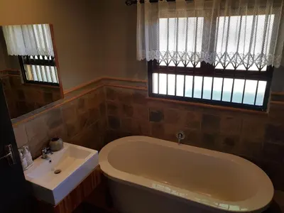 a bathroom with a tub and a sink and a window at El-Ruze in Baviaanspoort
