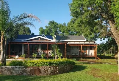 a house with a stone wall in a yard at El-Ruze in Baviaanspoort