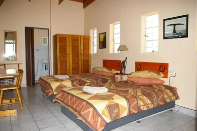 a bedroom with two beds and a table and a desk at Ingwe Guesthouse in Nelspruit