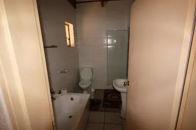 a bathroom with a tub and a toilet and a sink at Ingwe Guesthouse in Nelspruit