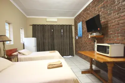 a hotel room with two beds and a brick wall at Ingwe Guesthouse in Nelspruit