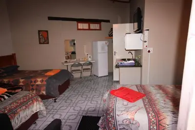 a hotel room with two beds and a refrigerator at Ingwe Guesthouse in Nelspruit