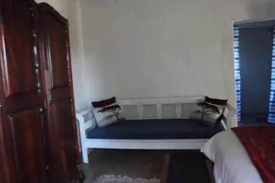a white bench in a room with a bed at Rustic Country Cottage in White River