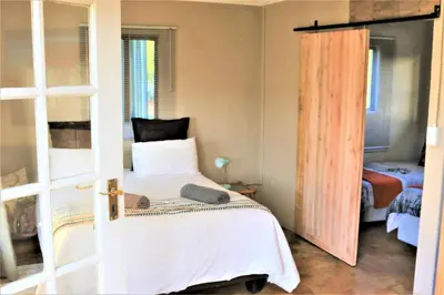 a bedroom with a bed with a cat laying on it at Round Here Self-Catering Holiday Home in Sabie